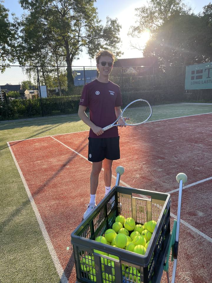 Ricardo met racket naast een mand vol tennisballen