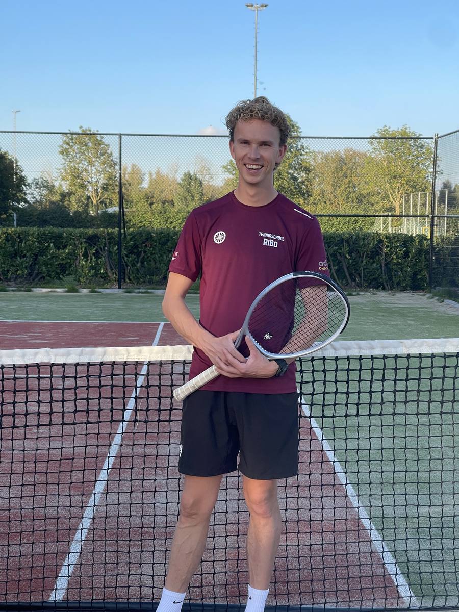 Ricardo in het shirt van Tennisschool RiBo, met racket bij het net